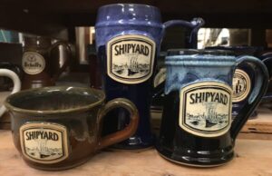 Three clay mugs with clay logo medallion imprint reading "shipyard brewery".