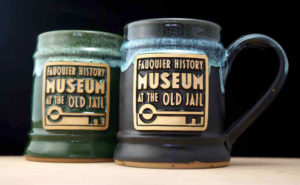 A dark green and black coffee mug with a museum logo.