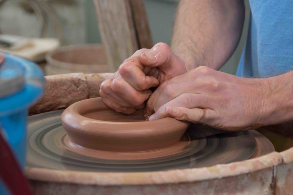 potter using a potter wheel to make a clay mug