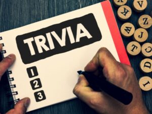 Hand holding a black marker over a note pad that reads "Trivia".