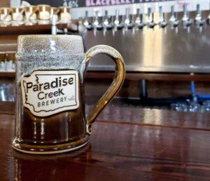 brown and white beer stein with logo that reads "paradise creek brewery'.