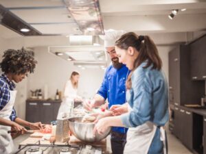 Chef showing two people how to cook.