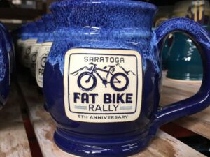 Blue beer mug with a clay medallion that features an illustration of a bicycle and the text "Saratoga fat bike rally".