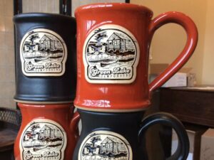 stack of four red and black coffee mugs with a summer camp logo