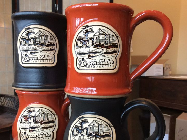 stack of four red and black coffee mugs with a summer camp logo