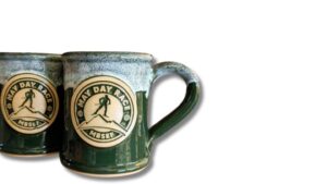 two green coffee mugs with a logo of a person skiing on them